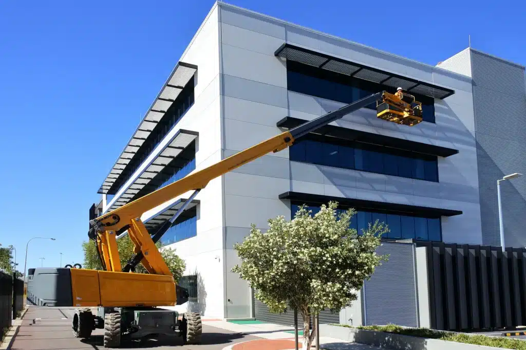 Boom lift raising worker for structural installation, emphasizing safe high-access operation.