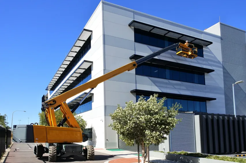 Boom lift raising worker for structural installation, emphasizing safe high-access operation.
