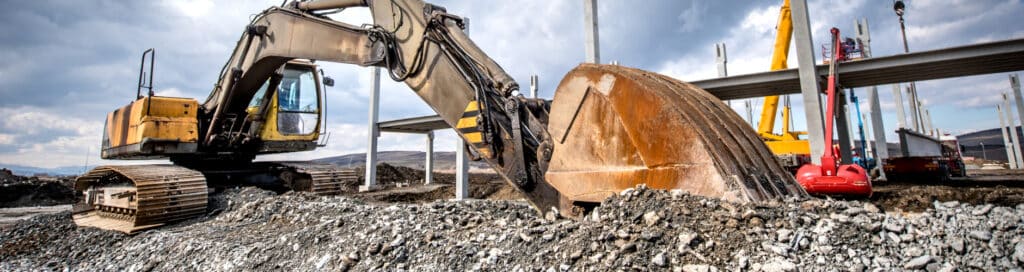 Heavy duty industrial excavator loading gravel on construction site. Details of building site