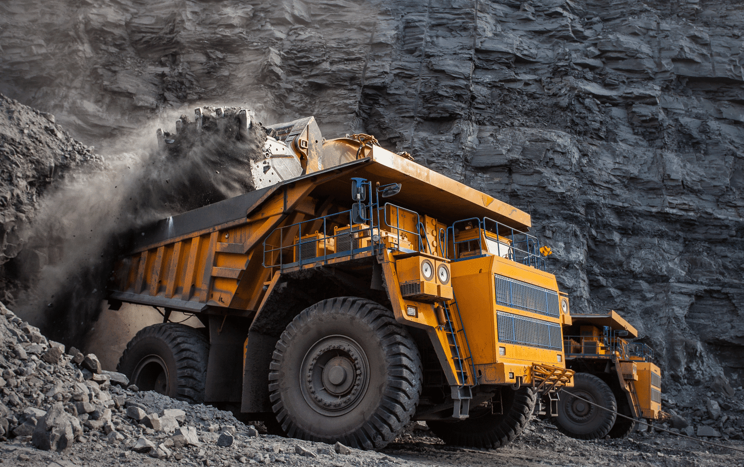 a piece of heavy equipment, a dump truck, gets loaded with gravel