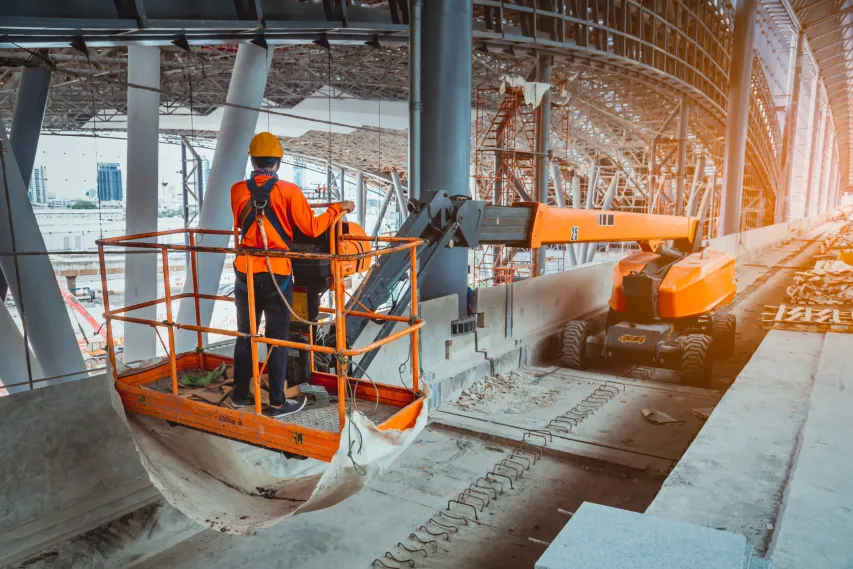 Worker using boom lift indoors with proper gear, demonstrating compliance during high-access tasks.