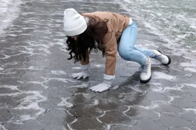 Same‑level fall on a slick surface caused by hidden ice during winter conditions.
