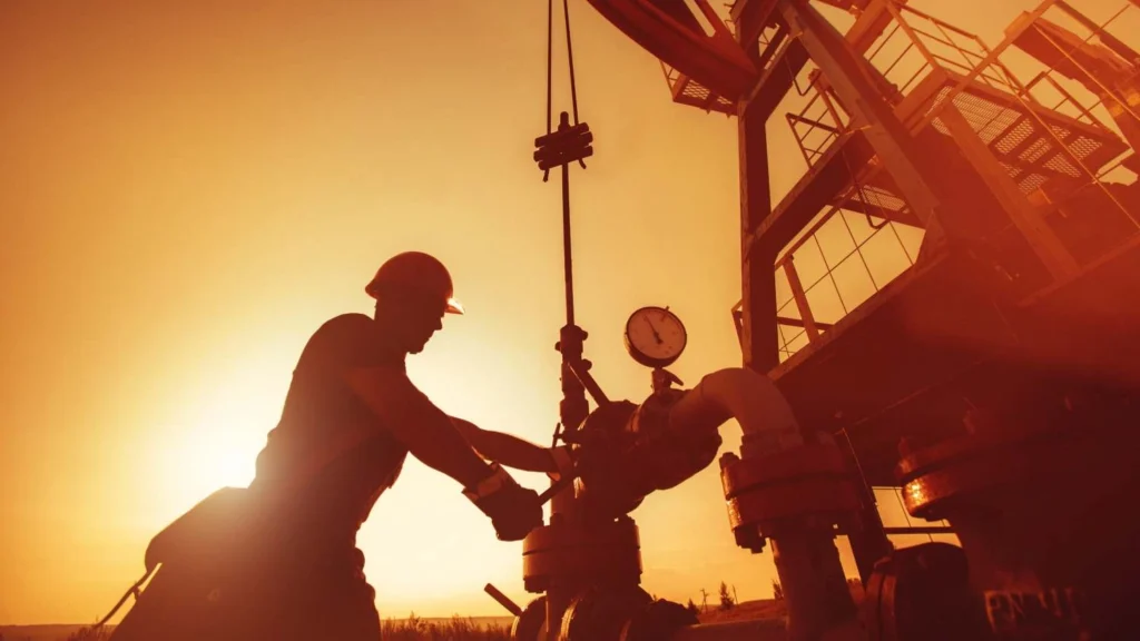 Oil worker is checking the oil pump on the sunset background.
