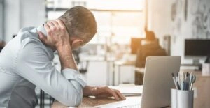 - BIS Safety Software Man holding sore neck while using notebook computer. He sitting at table. Sick worker concept