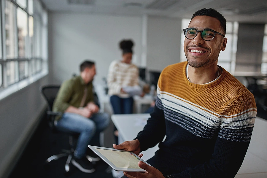 Smiling man in sweater in office holding tablet