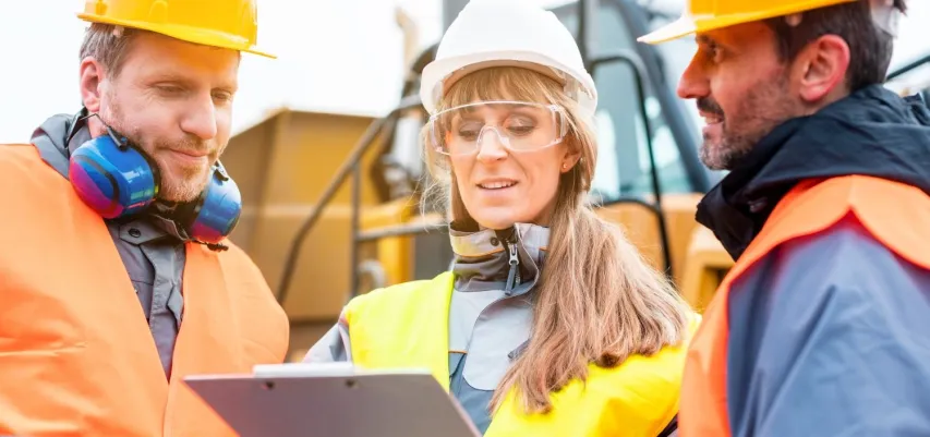 - BIS Safety Software Three workers in a quarry discussing in front of heavy machinery looking at plan