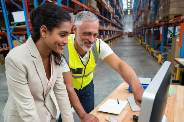 Workers on computer in warehouse