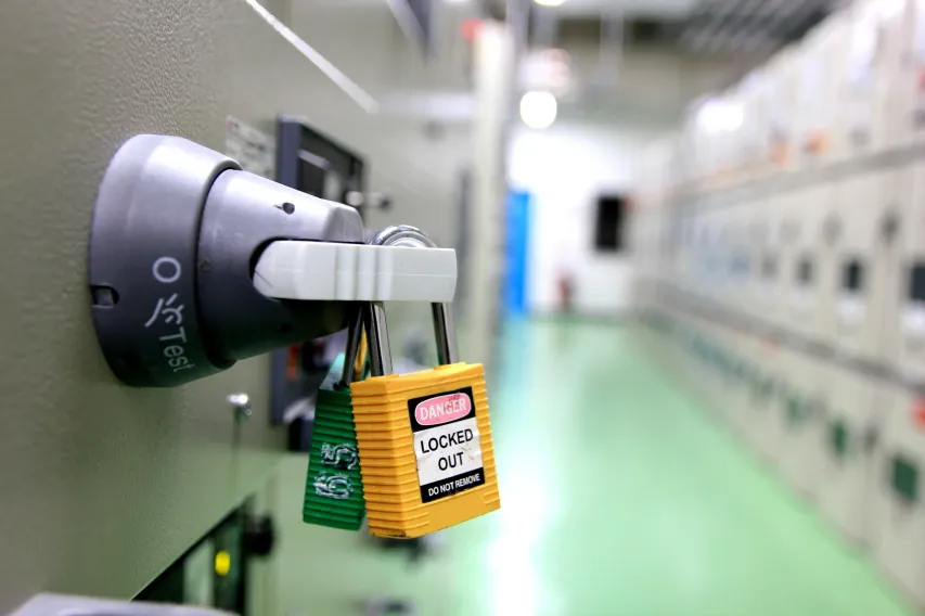 Worker applying a lockout tag to a control panel for energy isolation safety.