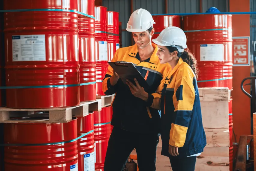 Safety professionals in hard hats reviewing chemical inventory for WHMIS compliance.