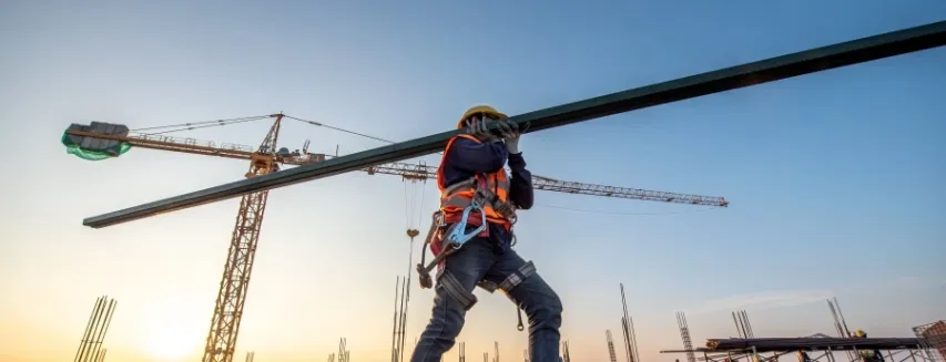 A construction worker carrying a beam at construction site