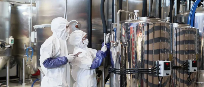 Wide angle view at two workers wearing protective suits while inspecting production at modern chemical plant, copy space