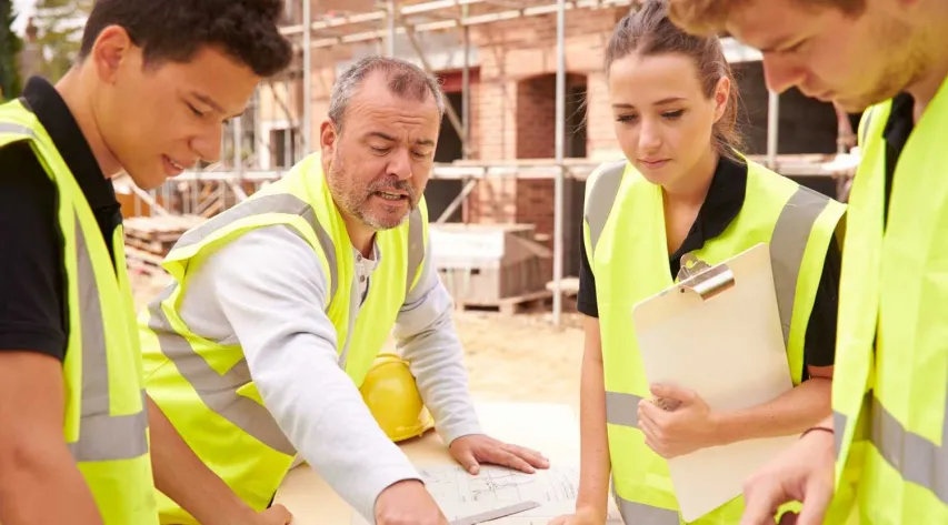 3 team members discuss workplace safety topics on a construction site.