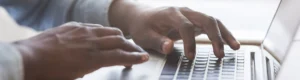 man typing on laptop keyboard in office