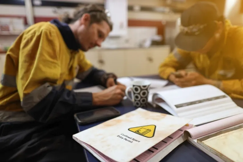 Two EHS reps fill out confined space report for compliance.
